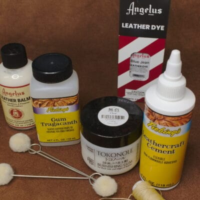 Leathercraft supplies including Tokonole, Fiebing’s adhesives, Angelus dye and edge tools on a brown suede background.