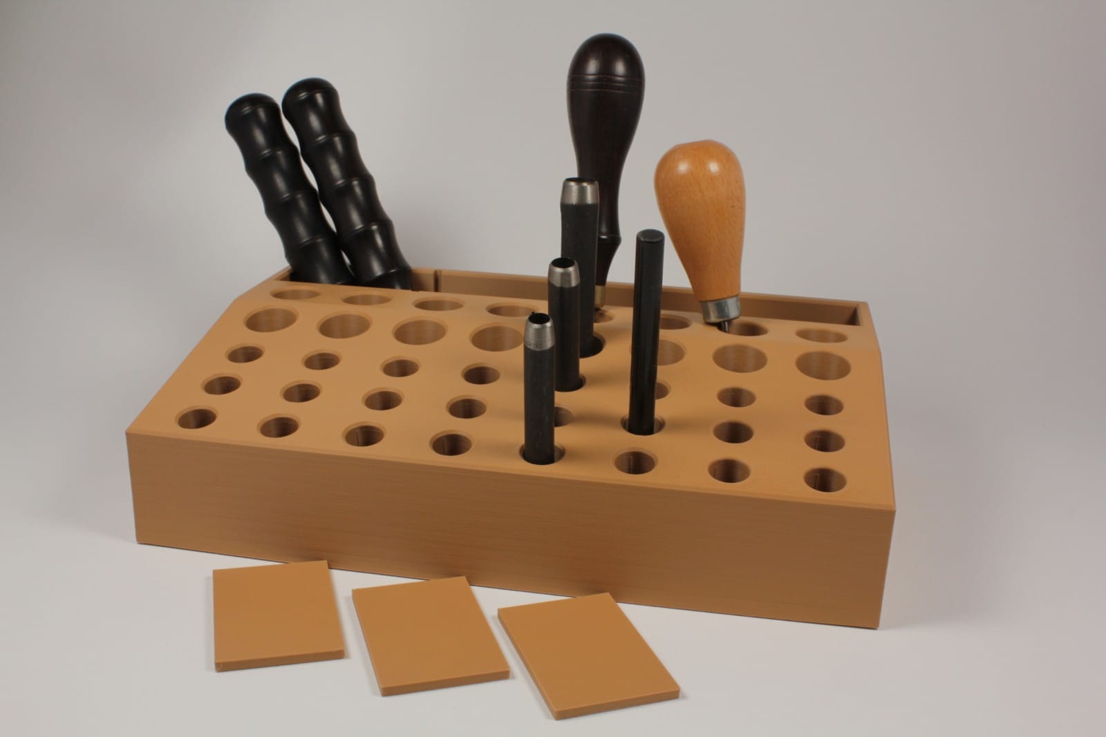 Hideout Craft modular leather tool holder in wood finish holding awls and punches on a workbench