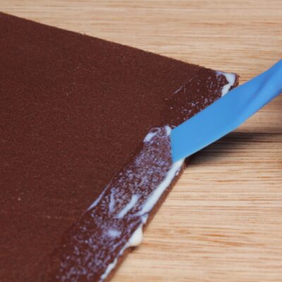 Blue plastic glue spreader applying contact adhesive to leather