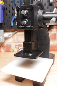 Arbor press foot adapter positioned above an HDPE cutting plate for leather die cutting.