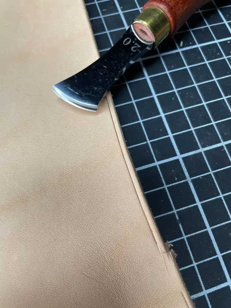 AIGAEER red-handle creaser marked 2.0 beside a piece of leather on a cutting mat