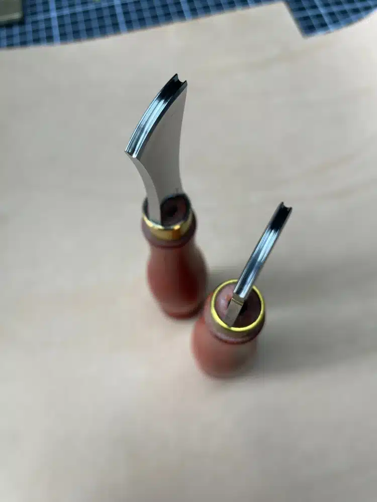 Top-down view of two AIGAEER red-handle creasers showing the grooved working edges of both heads