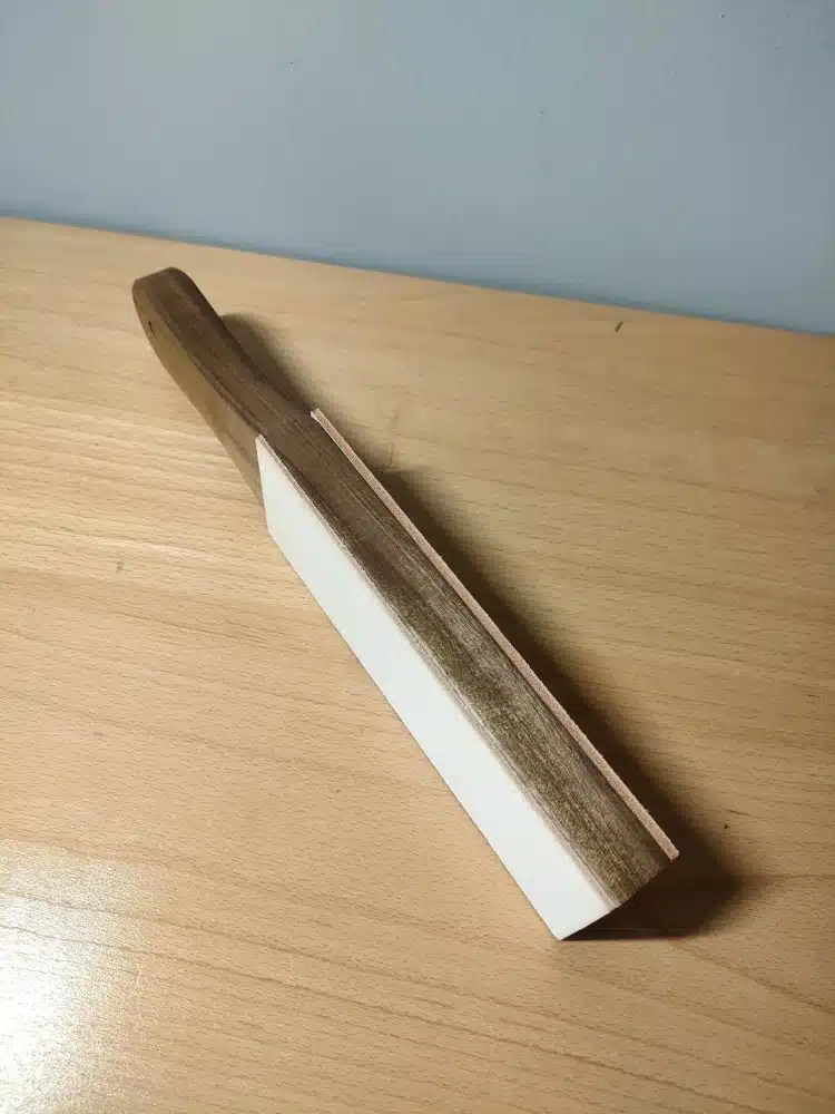 Side view of the Kevin Lee black walnut strop showing the white stropping surface and a tan-coloured layer along the opposite edge