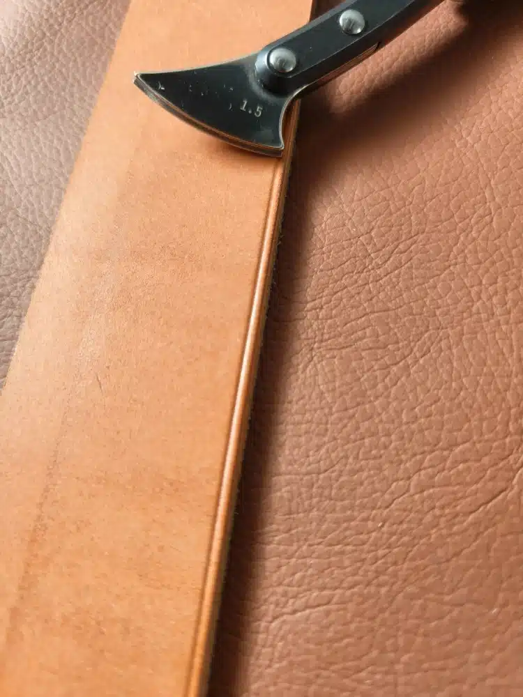 Kevin Lee G10-handle fixed creaser head marked 1.5 beside a crease line along the edge of a leather strap