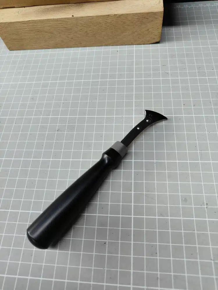 Reverse view of the Kevin Lee G10-handle fixed creaser showing the black handle and riveted head